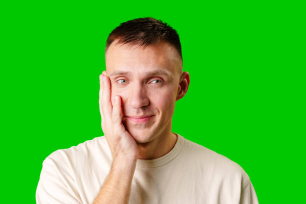 istock Young Man Smiling and Touching His Face Against a Bright Green Background 2169239363