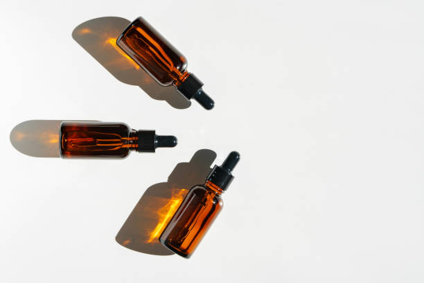 istock Arranged Amber Glass Bottles With Droppers on White Surface Accentuated by Shadows in Bright Light 2169240466