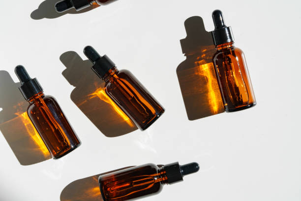 istock Arranged Amber Glass Bottles With Droppers on White Surface Accentuated by Shadows in Bright Light 2169241230