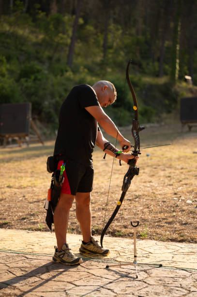 istock A man is standing in a field with a bow and arrow 2169244838