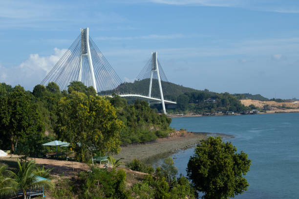 istock Jembatan Barelang or Barelang Bridge at  Batam Island, Indonesia, a bridge that connects Batam Island and Rempang Island. Cable-Stayed Bridge on Clear Sunny Day with Blue Sky and Empty Road in View 2169262561