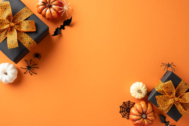 istock Halloween flat lay scene with pumpkins, gift boxes, bats, and spiders on an orange background 2169263465