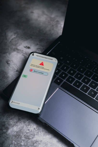 istock Smartphone laying on laptop receives message from suspected number scam 2169265104