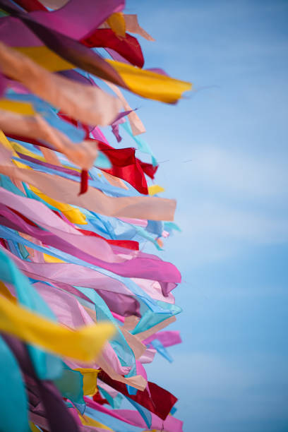 Color image of many colorful ribbons blown by the wind, against a blue sky.