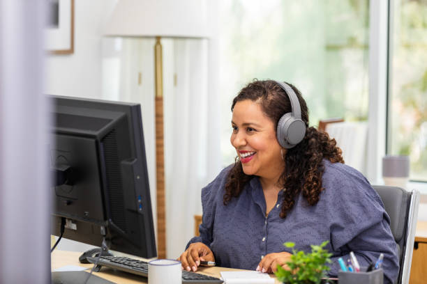 businesswoman smiles as she meets with client virtually - evden çalışma stok fotoğraflar ve resimler