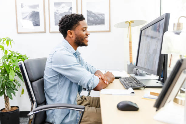 istock Young man smiles while participating in virtual meeting 2169270943