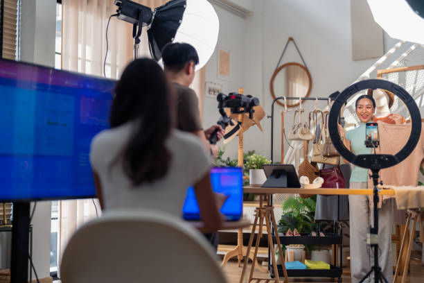 istock selling live stream online marketing behind back office woman programer checking selling statistic from application screen between stylish influencer woman broadcast selling cloth online SME small business e-commerce 2169281836