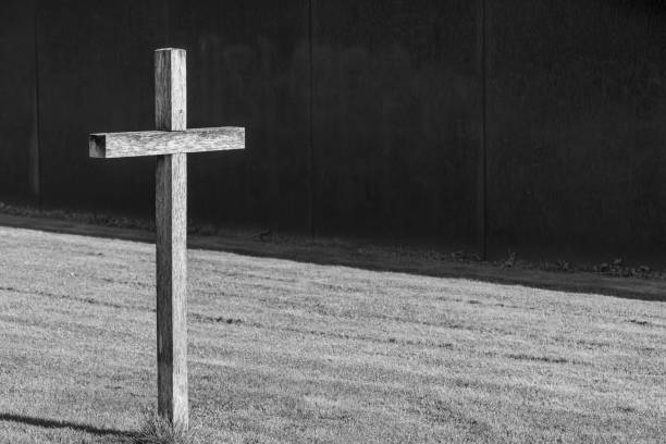 Germany, Berlin,  Central Berlin, August 27, 2024 - Cross on a meadow in front of a wall
