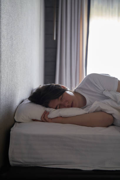 istock Young Woman Sleeping Peacefully in Bed by Window 2169283950