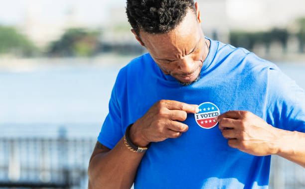 istock Man putting I Voted sticker on shirt 2169286737