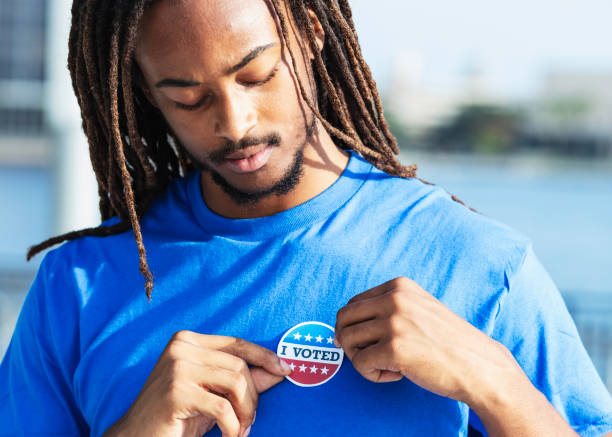 istock Young man putting I Voted sticker on shirt 2169286740