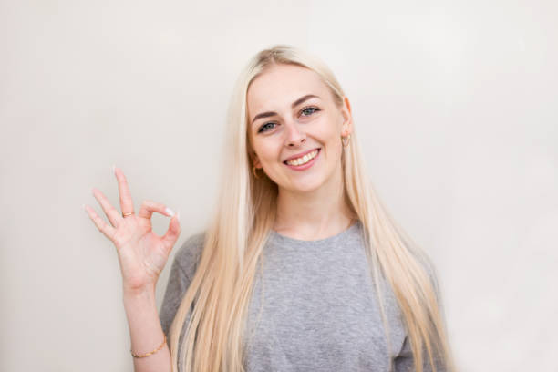 istock Young lighthearted girl shows okay gesture, isolated on beige 2169290056