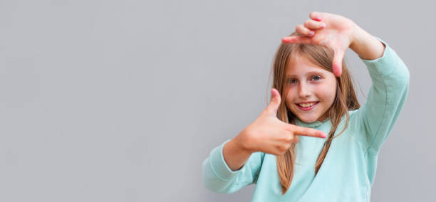 istock Smiling beautiful girl making frame gesture with fingers over gray background 2169292625