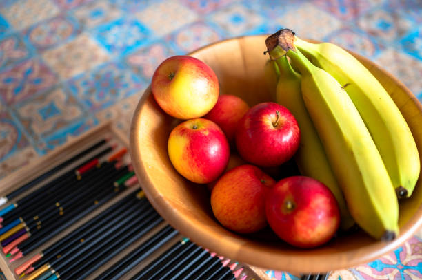 A banana lies over an apple and a pear sits on top of the banana