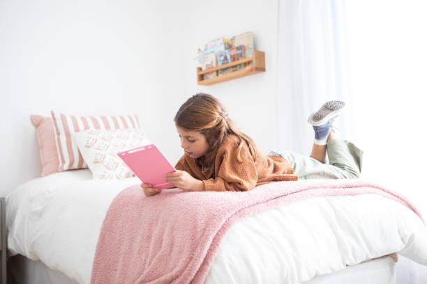 istock Beautiful 7 year old girl using a digital tablet in her bedroom 2169296460