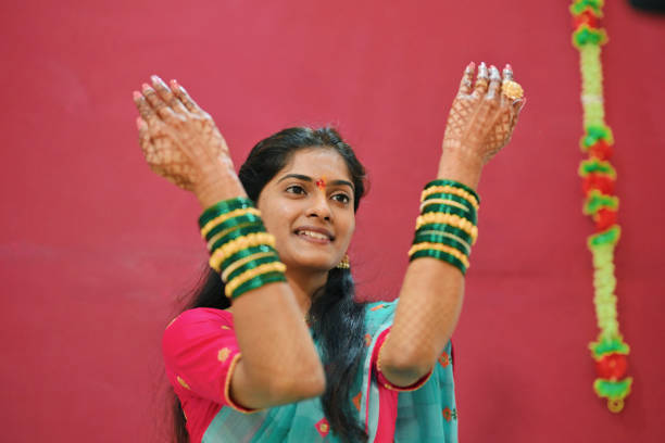 The bride is seen showing her beautiful green bangles during her pre-wedding rituals. Her hands, decorated with detailed mehndi, gently highlight the traditional bangles. The scene is showcasing cultural traditions in a simple, elegant way.