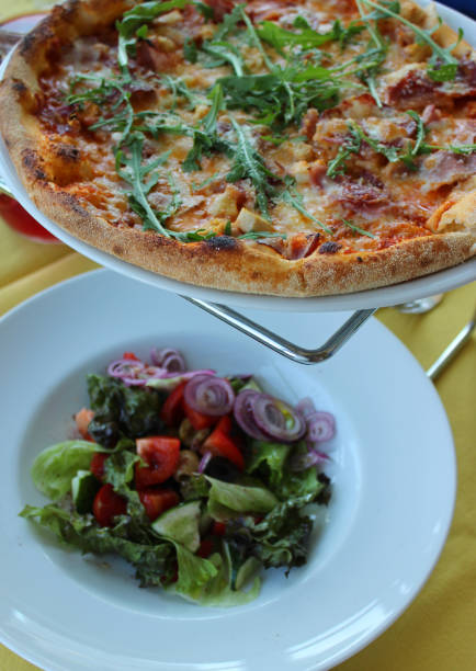 Restaurant Table Setting Set With Served Pizza On Table Stand And Fresh Vegetables Salad