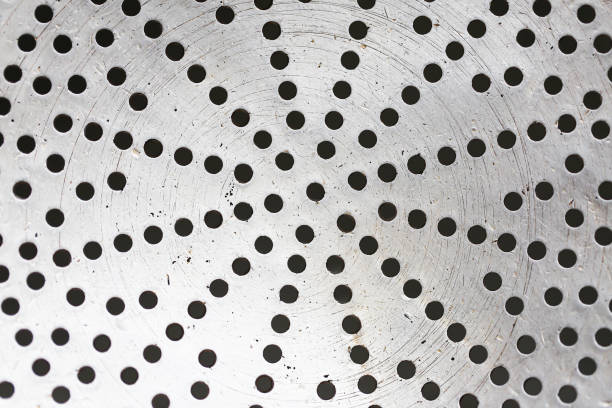 Metal kitchen strainer with a perforated surface. Small holes texture.
