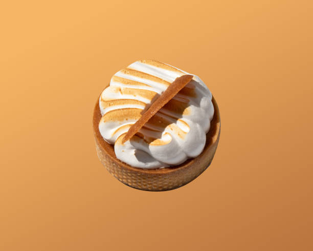 istock A small cake with meringue on an orange background. Dessert concept 2169311469