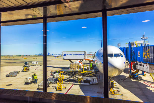 New York. USA. 08.29.2024. Commercial airplane at the gate undergoing catering service at an airport terminal with clear blue sky background.