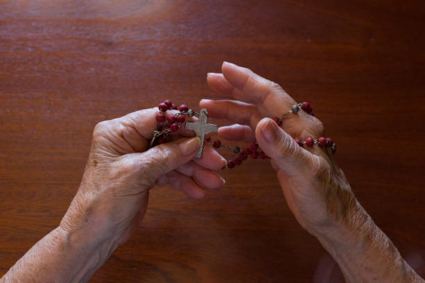 point of view of believing woman's hands caressing a Christian beaded rosary with a cross.devout parish nun of the Church. personal perspective of believing woman's hands caressing a Christian beaded rosary with a cross.praying a prayer to god.devout parish nun of the Church. religion and catholic culture. nun praying cross human hand stock pictures, royalty-free photos & images