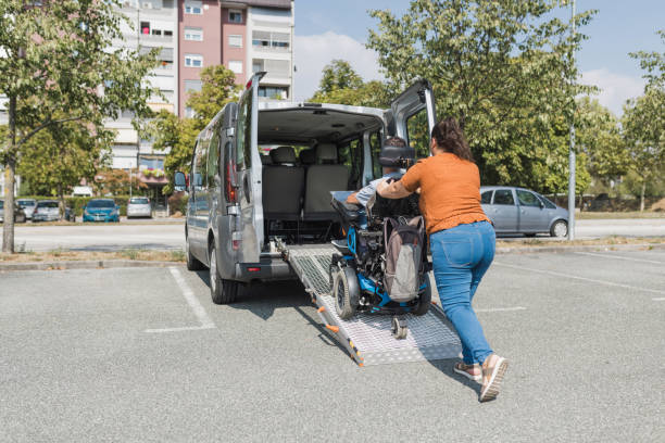 istock Assistant pushing a man with a disability over a wheelchair car ramp 2169336661