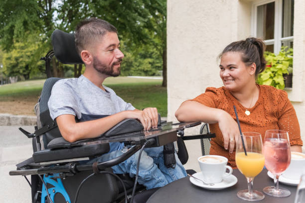istock Wife helping her husband with a disability drink juice in a cafe 2169337311