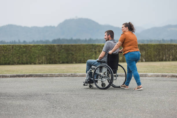 istock Assistant helping a man with reduced mobility in a wheelchair to move 2169337410