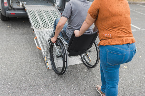 istock Assistant helping a person in wheelchair with transport using accessible ramp 2169337449
