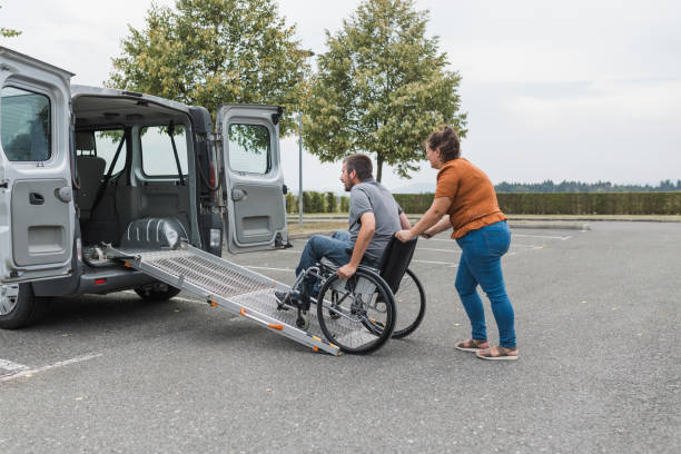 istock Assistant helping a person in wheelchair with transport using accessible ramp 2169337502