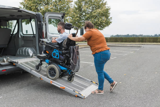 istock Assistant pushing a man with a disability over a wheelchair car ramp 2169337515