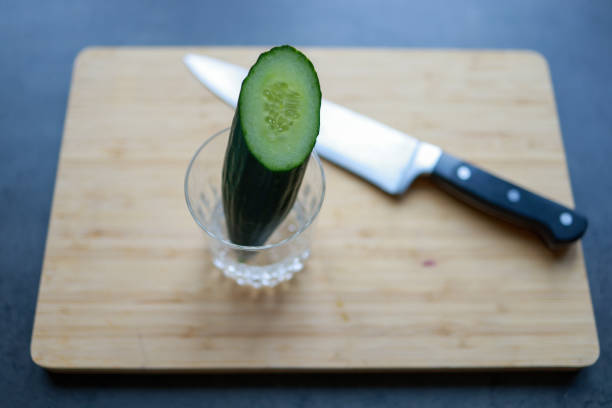 Cucumber cut in a glass with a knife on a cutting board for salat