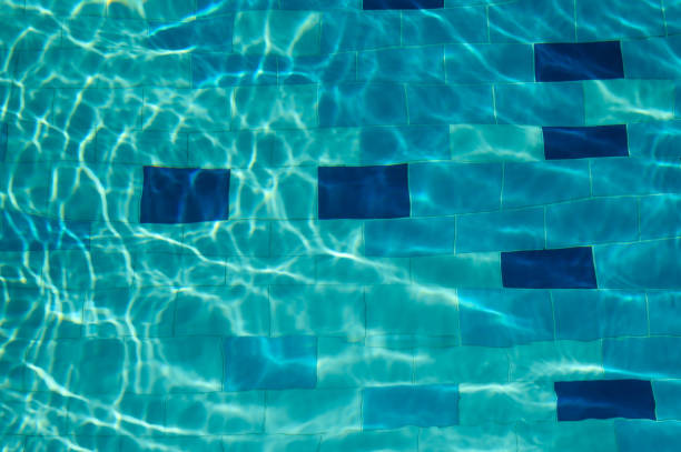 Underwater view of sunlight reflecting on the swimming pool floor background
