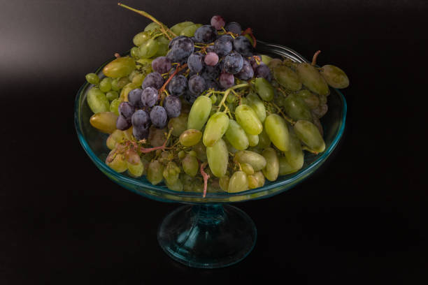 istock White and blue grape clusters on vintage vase on black 2169355094