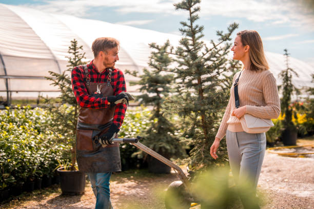 istock Caucasian Gardener Assists Female Customer with Potted Tree 2169361276