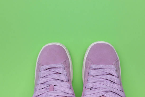 Pair of pink colored simple sneakers on wood background