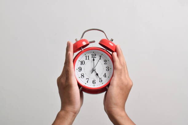 istock Male hand holding red alarm clock isolated 2169370096