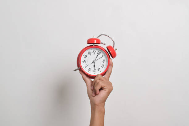 istock Man holding red alarm clock in hand 2169370409