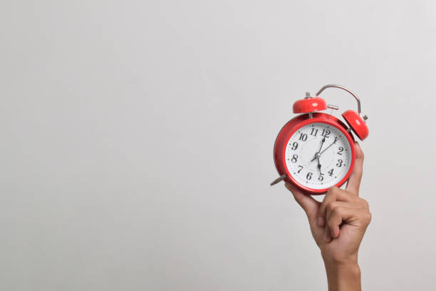 istock Man holding red alarm clock in hand 2169370447