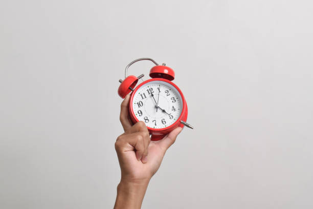 istock Man holding red alarm clock in hand 2169370493
