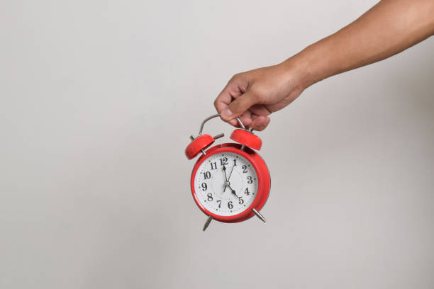 istock Man holding red alarm clock in hand 2169370523