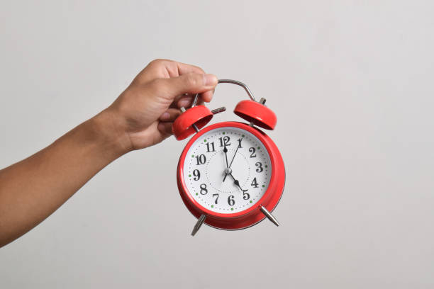 istock Man holding red alarm clock in hand 2169370552