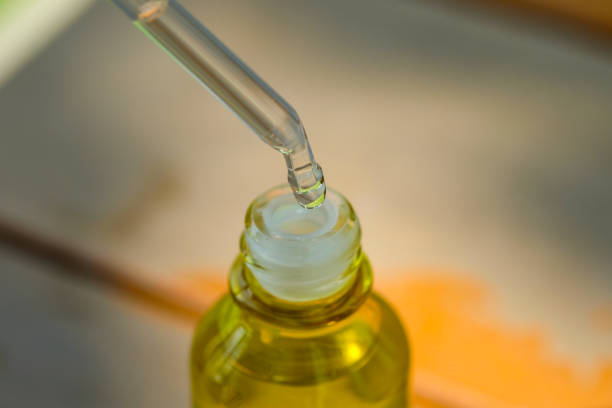 Dropping serum collagen moisturizer of face into clear yellow bottle soft light background. Protector skin Treatment facial essence oil, Vitamin C. Beauty and spa Concept.