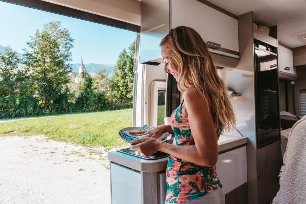 istock Woman Doing Dishes in Camper Van Kitchen with Scenic View 2169385121