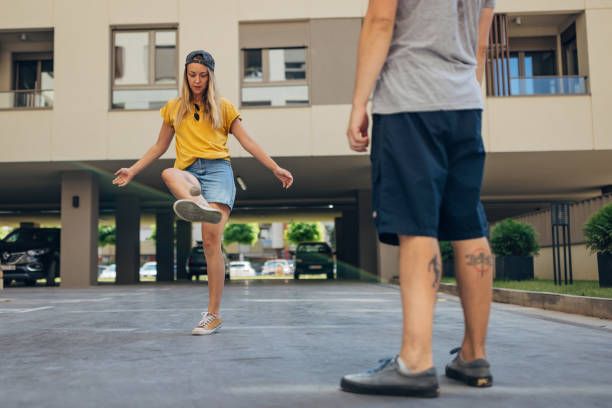 Two best friends are having crazy fun playing a game called hacky sack. The point of the game is to balance the footbag and throw it in the air