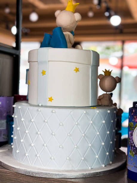 A charming two-tiered white cake decorated with teddy bears, crowns, and stars, perfect for a celebration.