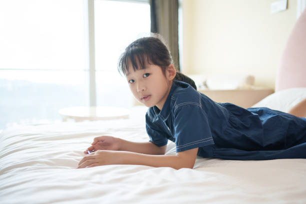 Portrait of Asian preteen girl child looking camera while relax on pink sofa bed on summer holiday.
