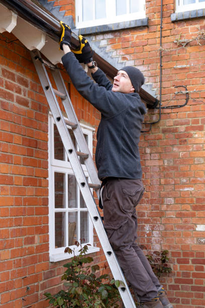 istock Man on a ladder fixing rain gutter on a UK house 2169392529