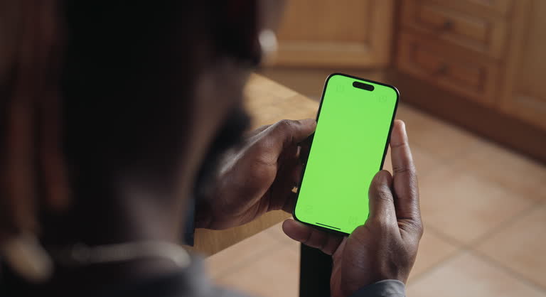 Close-up of a black man tapping on the green screen of his smartphone