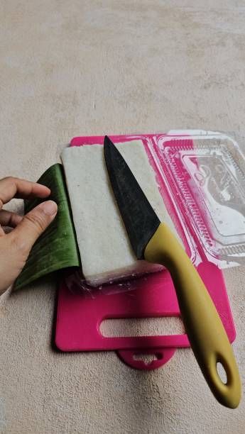 istock Raw sticky rice or ketan uli wrapped in banana leaves, cut into rectangular pieces, on a pink cutting board. 2169393389